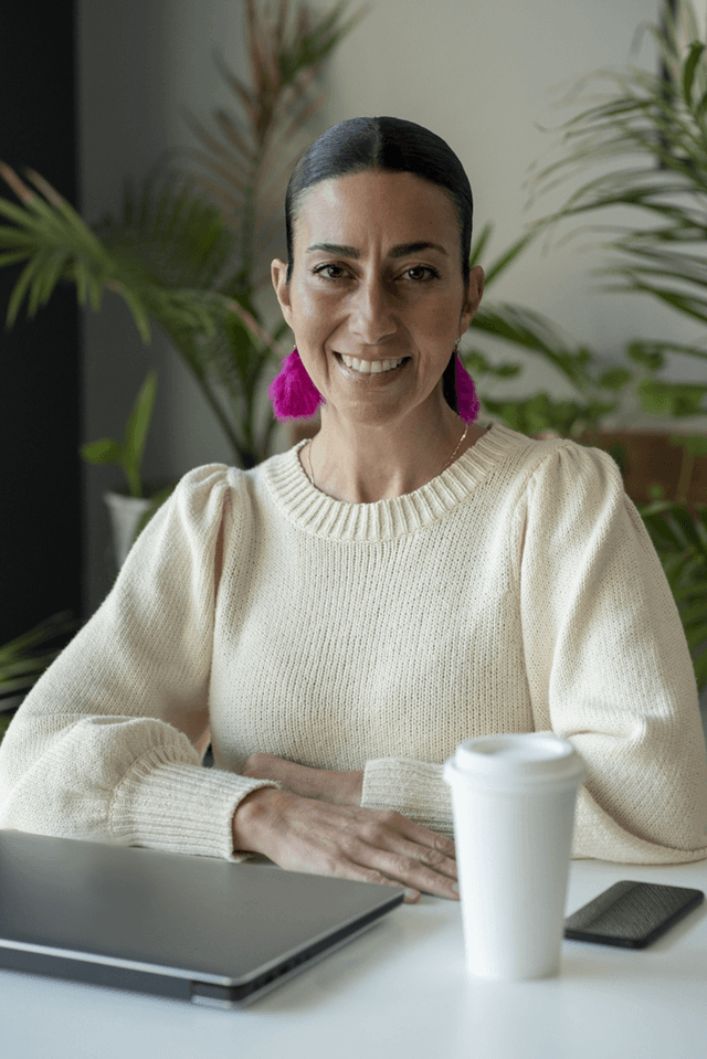 Indigenous woman sitting at her desk, smiling